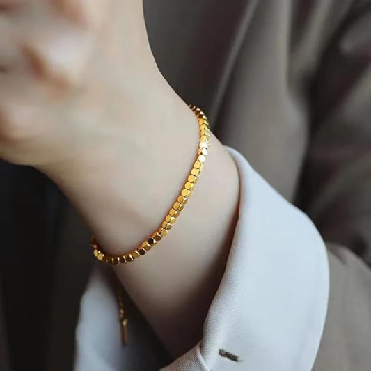 Elegant woman's wrist adorned with a gold bracelet, adding a touch of sophistication.