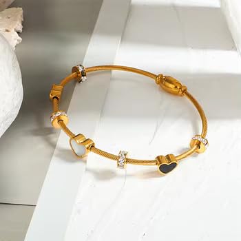 A chic gold bracelet embellished with black and white heart motifs, offering a sophisticated accessory for various occasions.