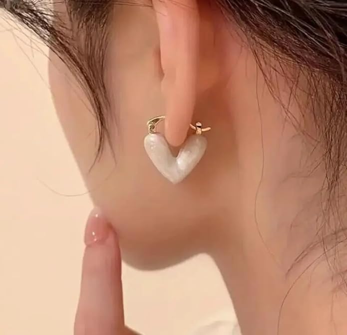Elegant white heart earrings against a soft beige backdrop, ideal for a chic and romantic look.