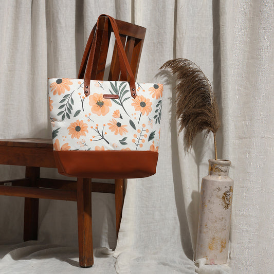 A stylish tote bag featuring a floral print, constructed from a blend of canvas and leather for durability and elegance.