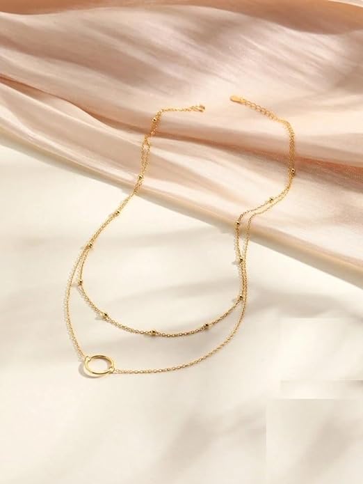 A gold circle layered necklace on a white background.