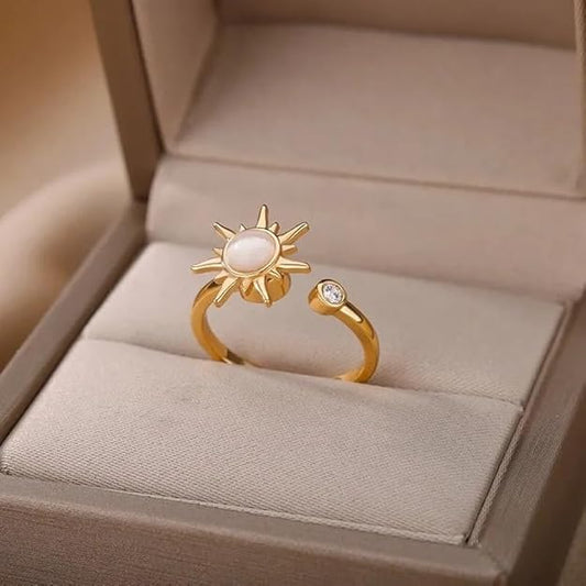 A gold ring with a white stone designed as a sun.