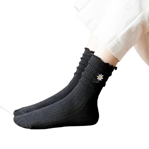 A woman's feet in black socks decorated with white daisies, showcasing a playful and stylish design.