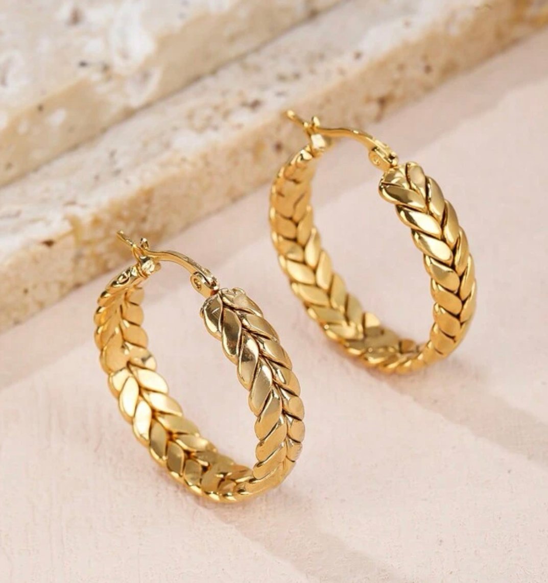 Shiny gold plated hoop earrings on white background.