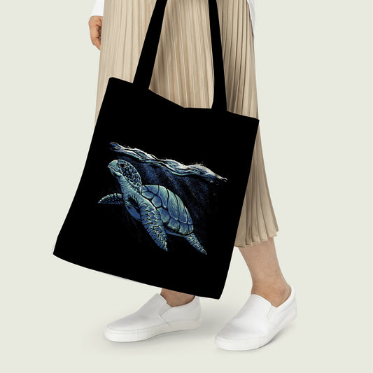 Women carrying a Tote Bag with Blue Sea Turtle Print on black background color, which can be used for everyday task