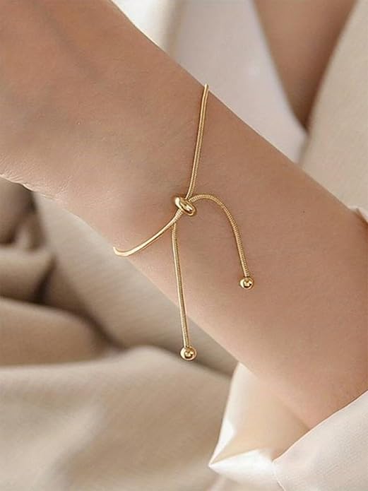  A shiny gold bracelet with a delicate gold chain, perfect for adding a touch of elegance to any outfit.