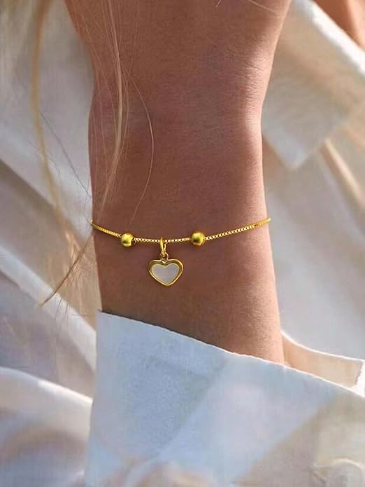  A shiny gold heart charm bracelet resting on a box.