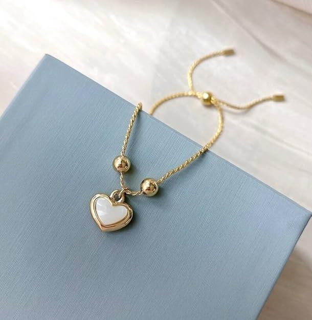 Gold heart charm bracelet displayed on a box.