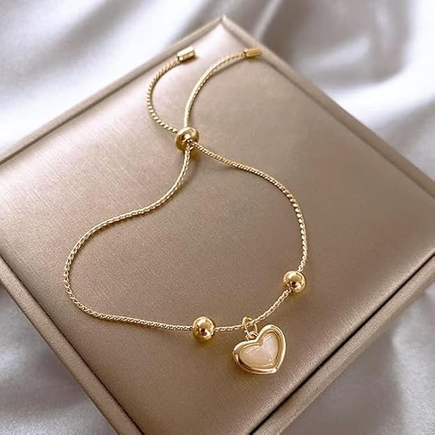  A gold heart charm bracelet resting on a box.