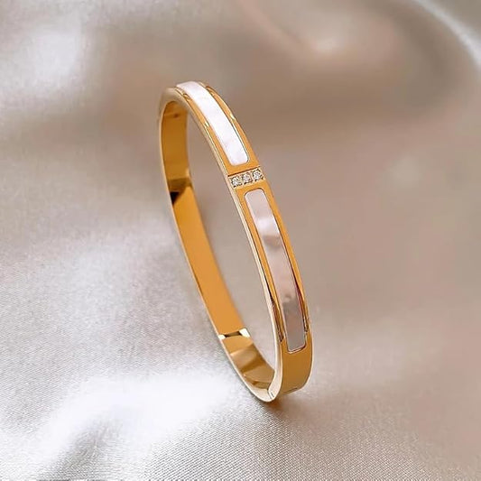 A gold bracelet with a diamond in the center.