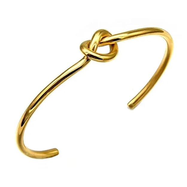 Gold cuff bracelet adorned with a stylish knot design.