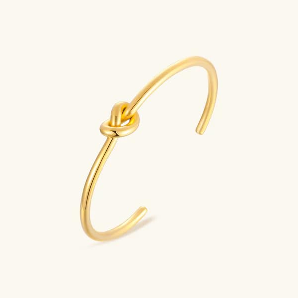 A stylish gold cuff bracelet featuring a chic knot design, perfect for adding a touch of elegance to any outfit.