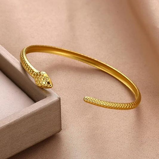 A shiny gold snake bracelet displayed on a box.