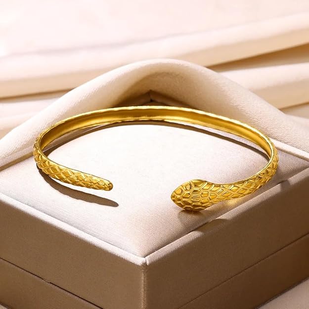 Gold snake bracelet resting on top of a box.