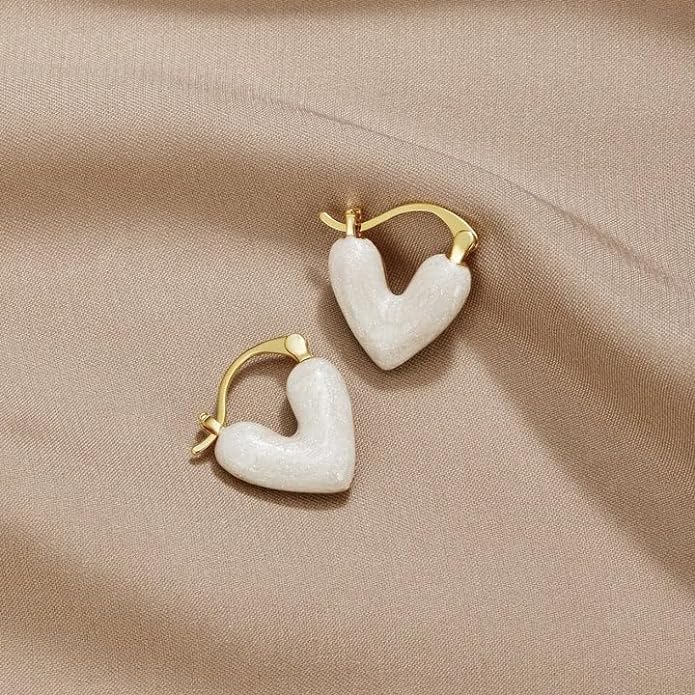 White heart earrings on beige background, a lovely accessory to enhance your overall style.