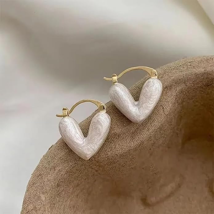 Stylish heart-shaped earrings in white, set on a neutral beige background for a classic touch.