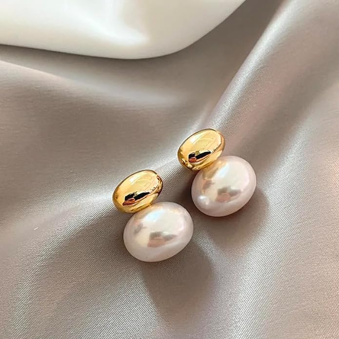 Classic white pearl earrings set on white fabric, adding a touch of sophistication.