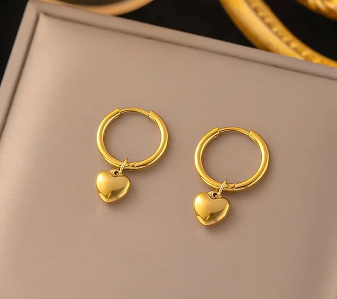 Two gold heart-shaped earrings on a plate.