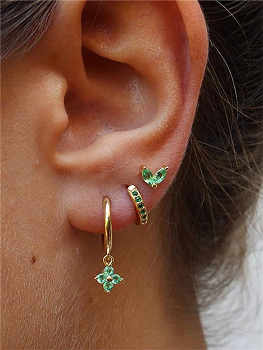 A woman wearing green earrings and a butterfly charm.