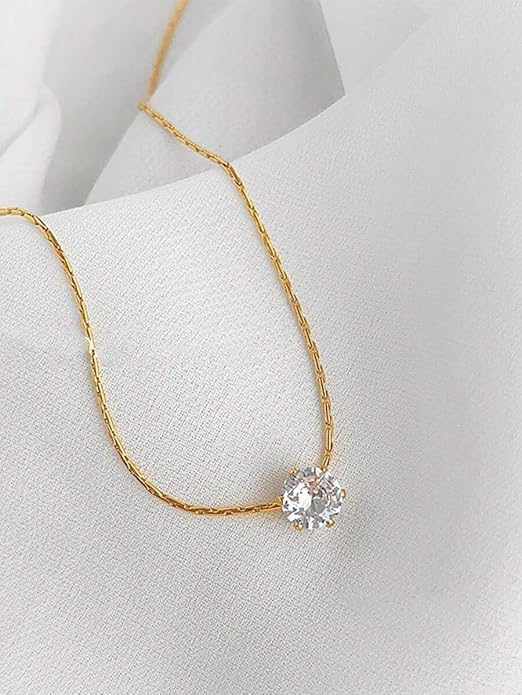 A white diamond sparkles on a gold plated necklace, a symbol of elegance.