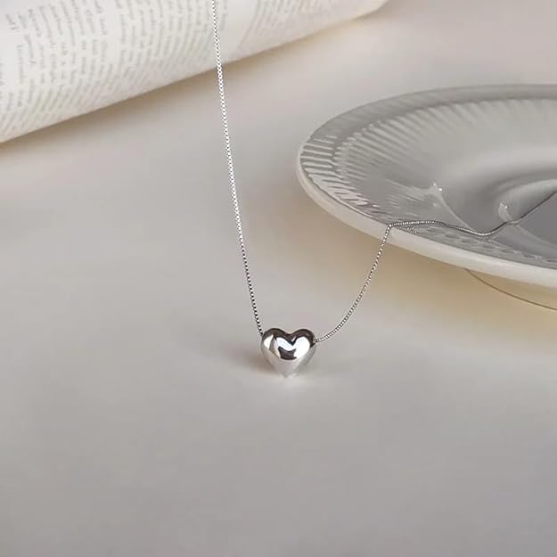 A heart-shaped pendant rests gracefully on a silver chain, embodying a classic and romantic jewelry piece.