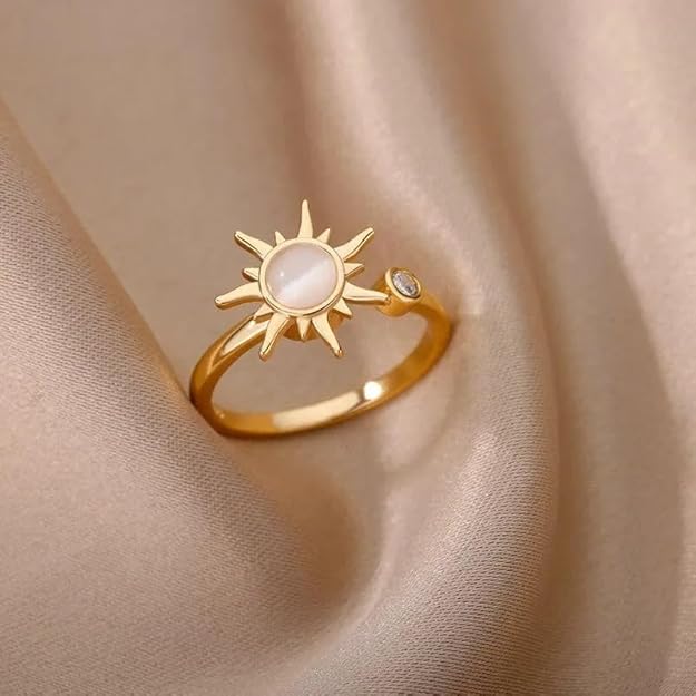 A gold ring with a white stone in the shape of a sun.