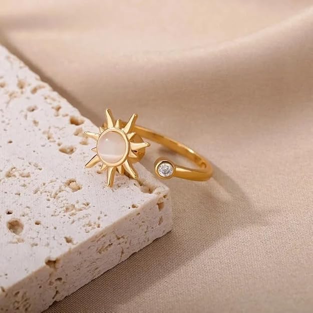 A gold ring featuring a white stone in the form of a sun.