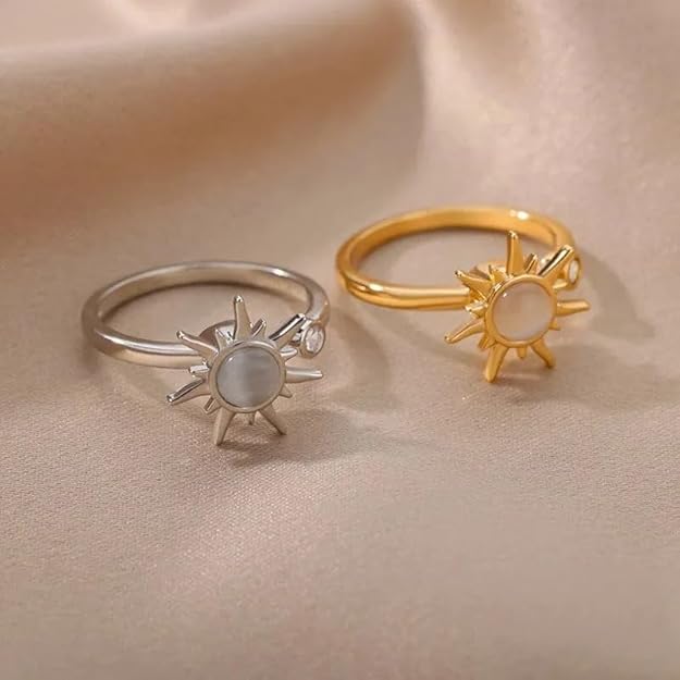 A white stone set in a gold ring shaped like a sun.