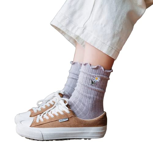 A woman dressed in white pants and sneakers stands confidently, showcasing a casual yet stylish outfit.