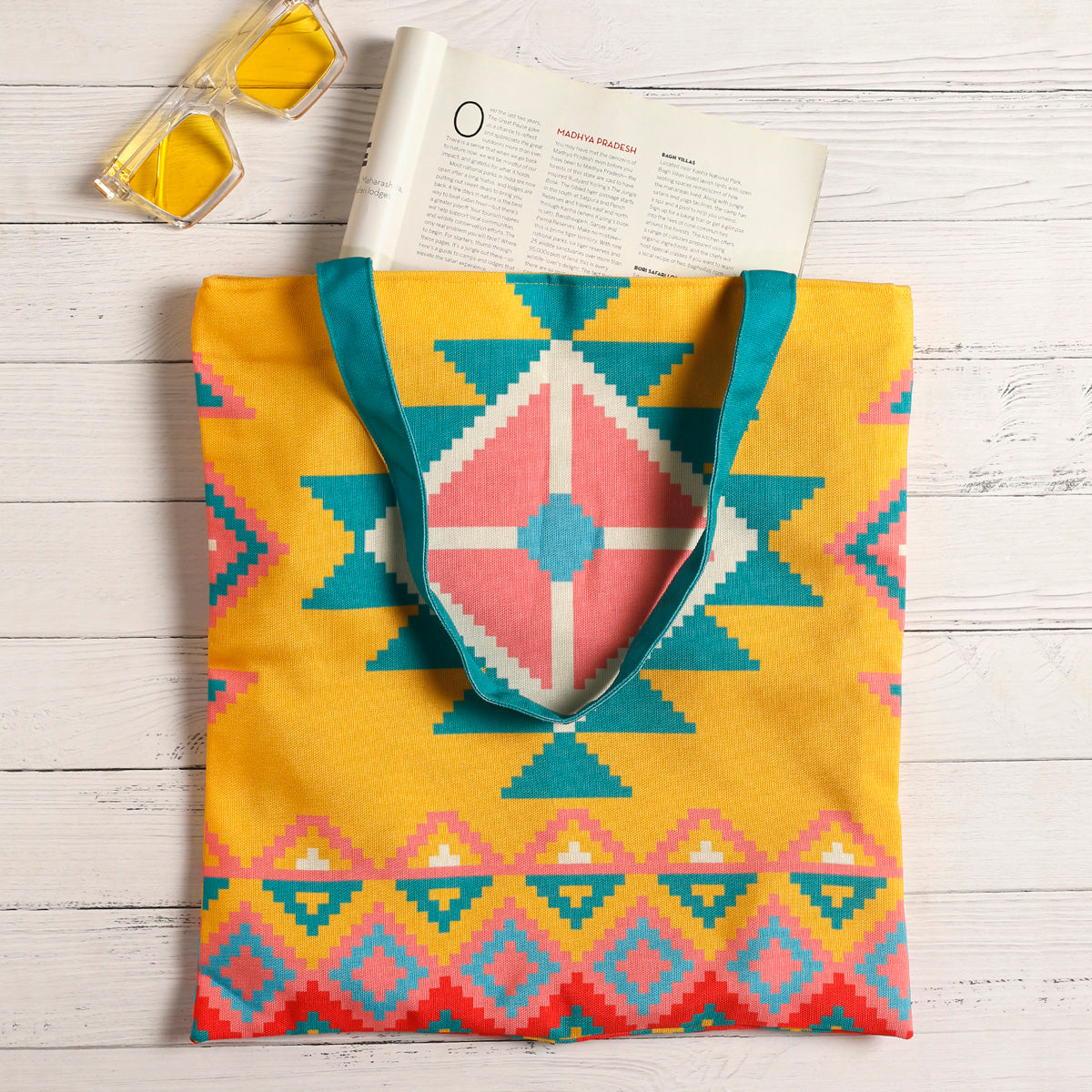 A tote bag with yellow and blue colors and a pink and turquoise design.