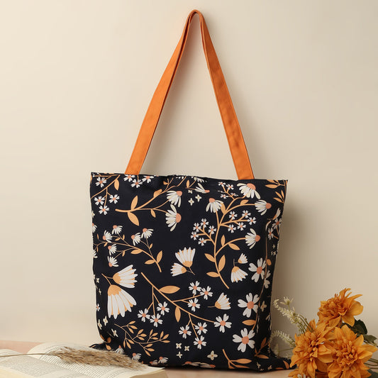 A floral tote bag with bright orange handles.