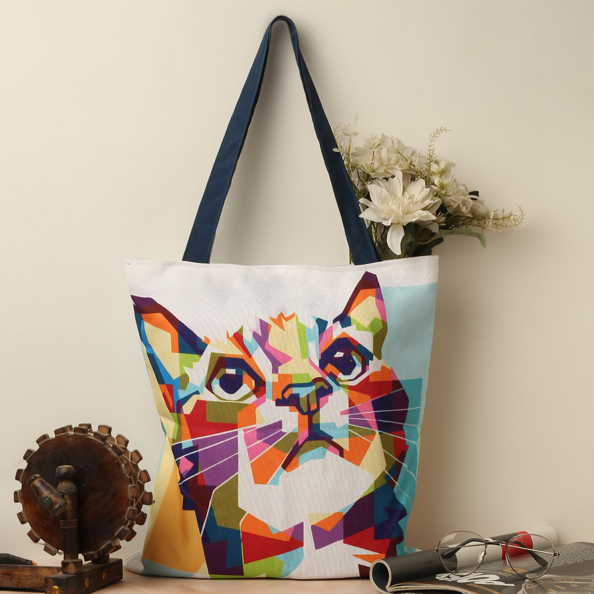 A tote bag with a vibrant cat face design.