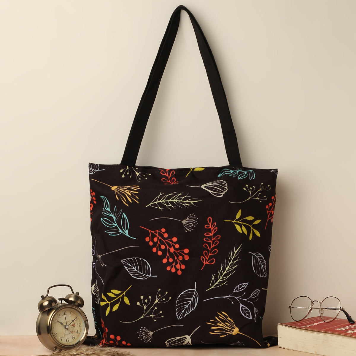  A black tote bag with vibrant leaves and flowers.