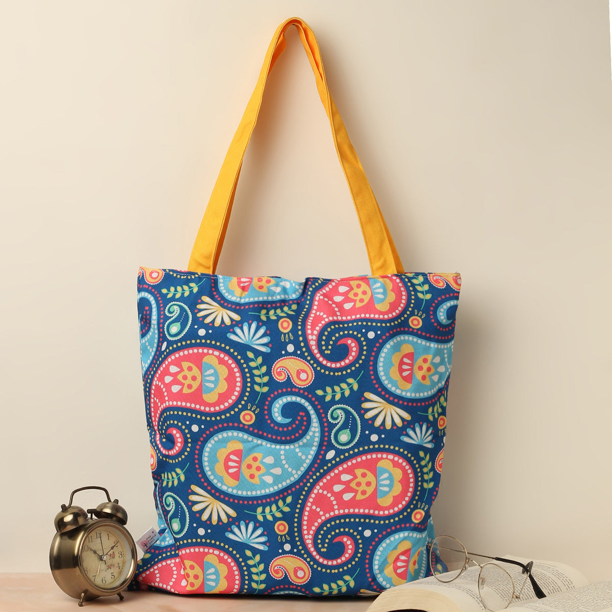 Colorful paisley pattern tote bag with yellow handles, perfect for adding a pop of color to your outfit.