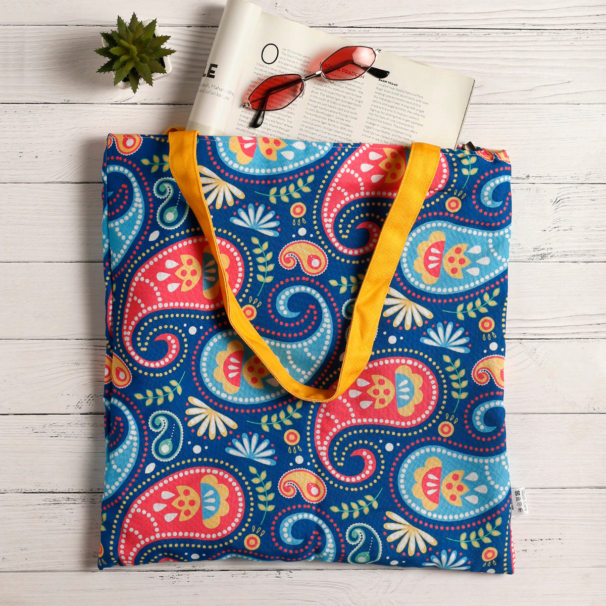 Vibrant paisley print tote bag featuring yellow handles, ideal for carrying your essentials in style.