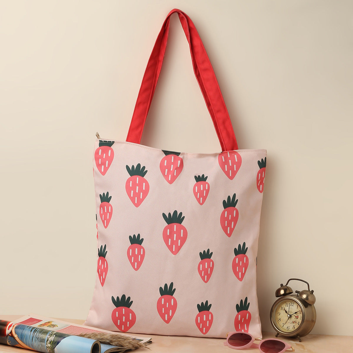 A pink tote bag adorned with vibrant strawberries, perfect for summer outings and casual shopping trips.