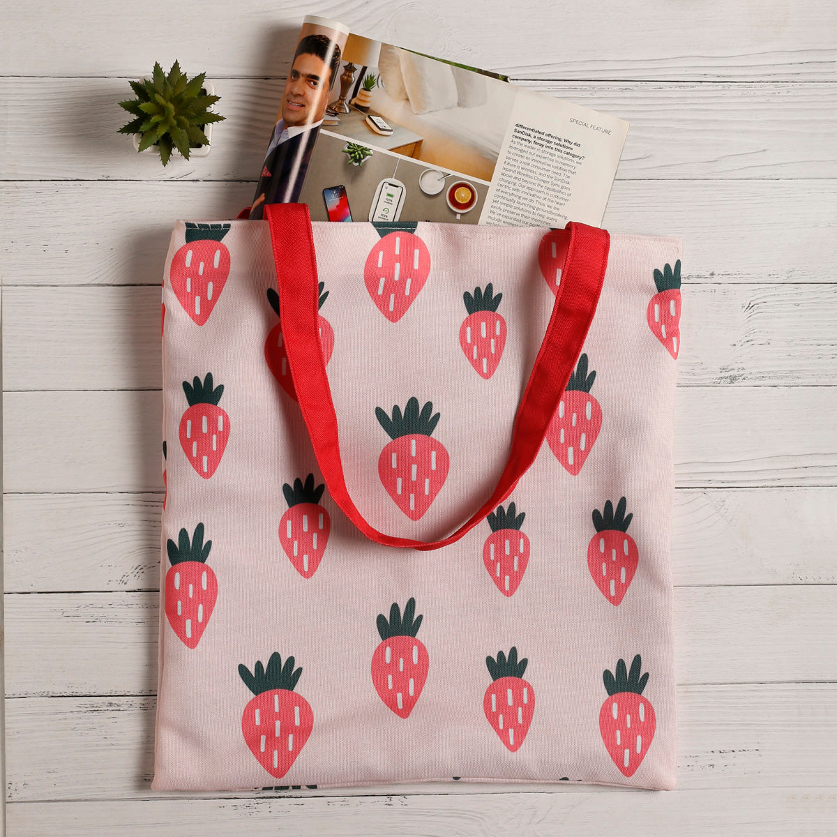 A stylish pink tote bag featuring a playful strawberry pattern, ideal for carrying essentials with a touch of fun.