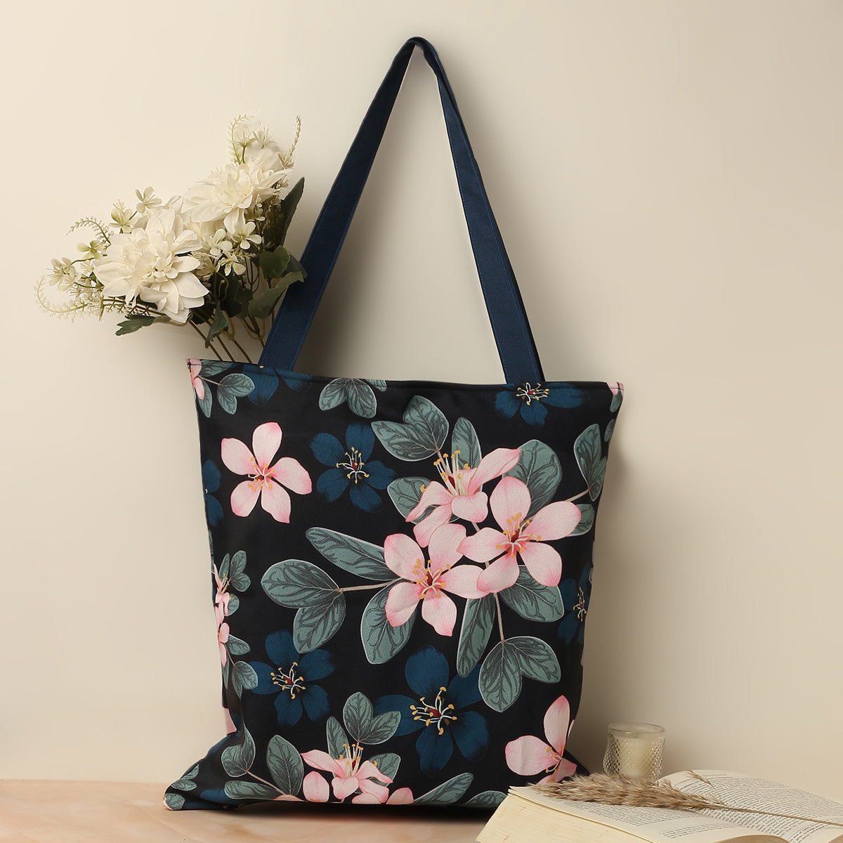 Black and blue floral tote bag featuring vibrant flowers, perfect for adding a pop of color to your outfit.