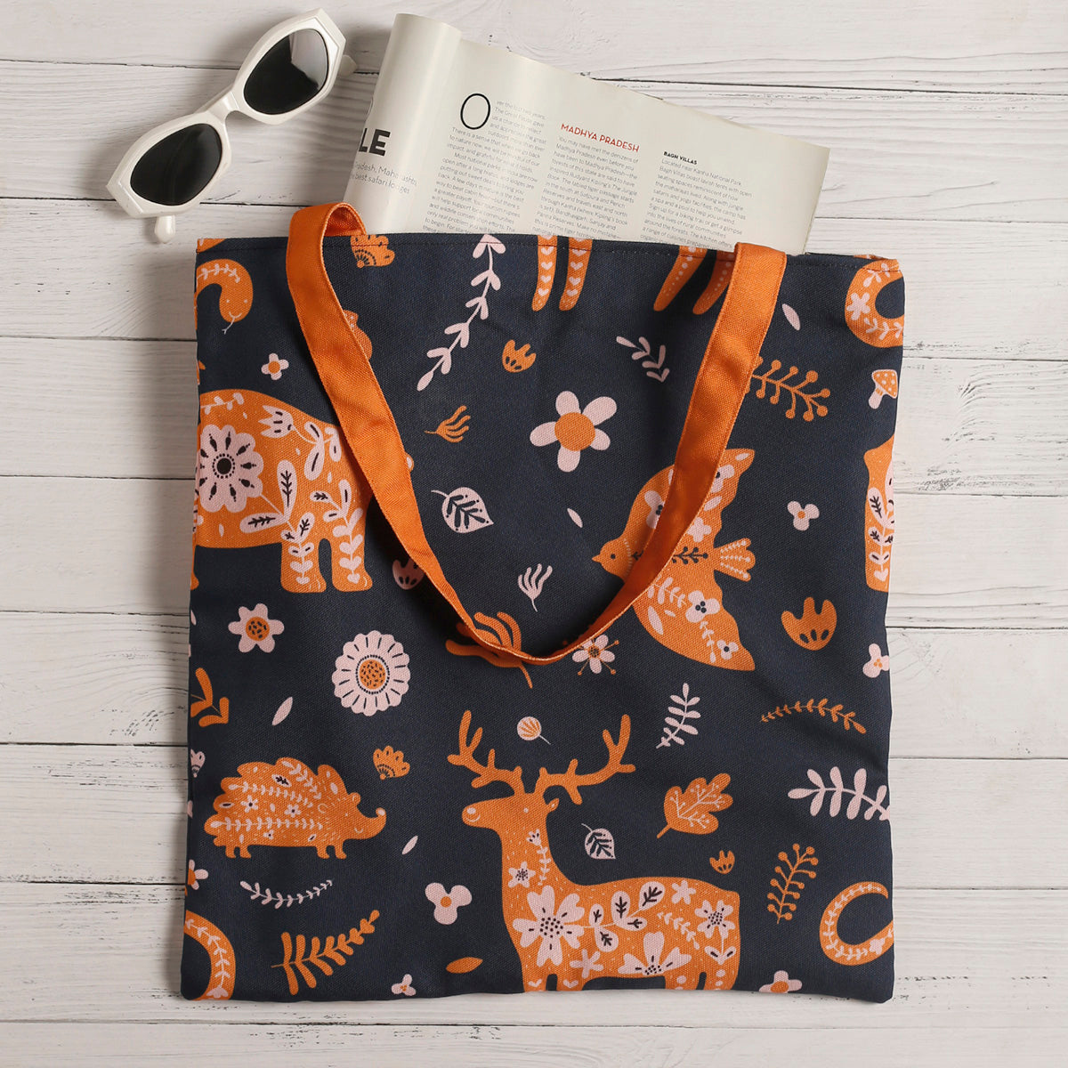 Stylish tote bag with deer and flowers design and orange handle.