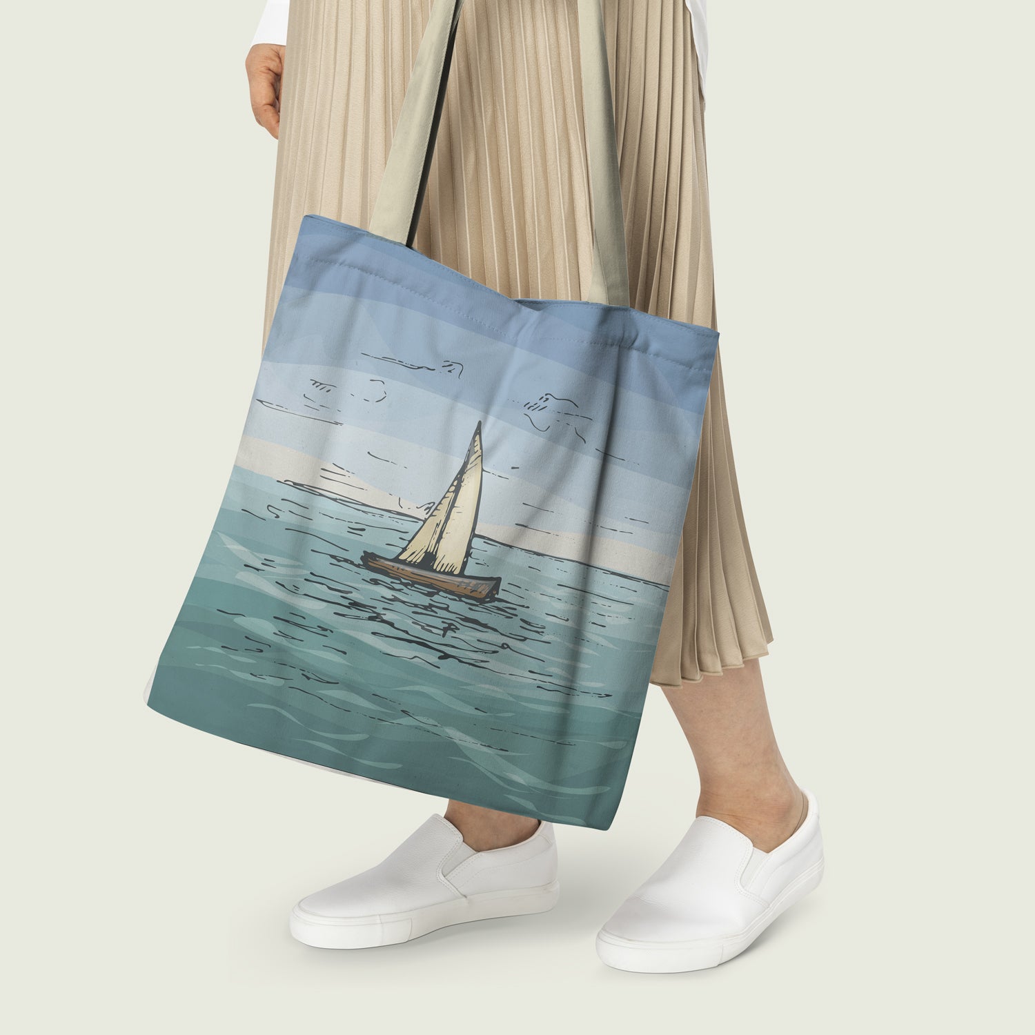 Women Carrying a tote bag with print of a boat sailing on the ocean with a beautifull picture of the sky and the ocean. Bag is blue and yellow in color with color matching handles.