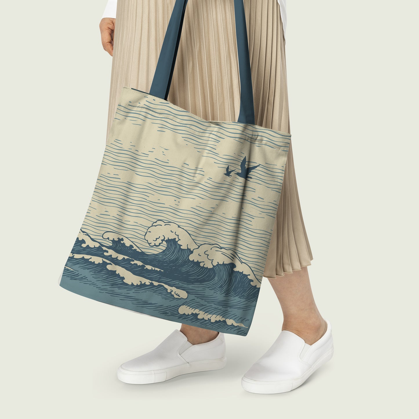 Women carrying a tote bag with prints of huge sea waves carrying out with a wide open sky above where birds are flying.